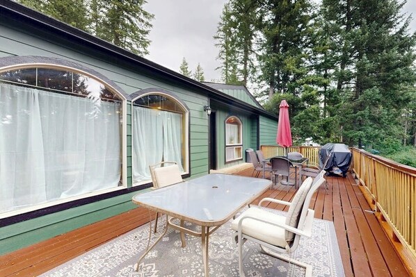 Eine überdachte Terrasse mit Gartenmöbeln, einem Tisch und Stühlen.