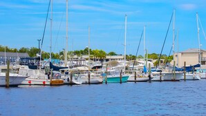 A marina with multiple boats docked, a clear sky, and buildings in the background. - Renovated Gulf Coast Home - Walk to Marina, Dining, & Downtown Carrabelle (Carrabelle)