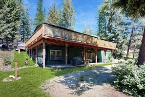 Eine zweistöckige Holzhütte mit einer Veranda, umgeben von Bäumen.