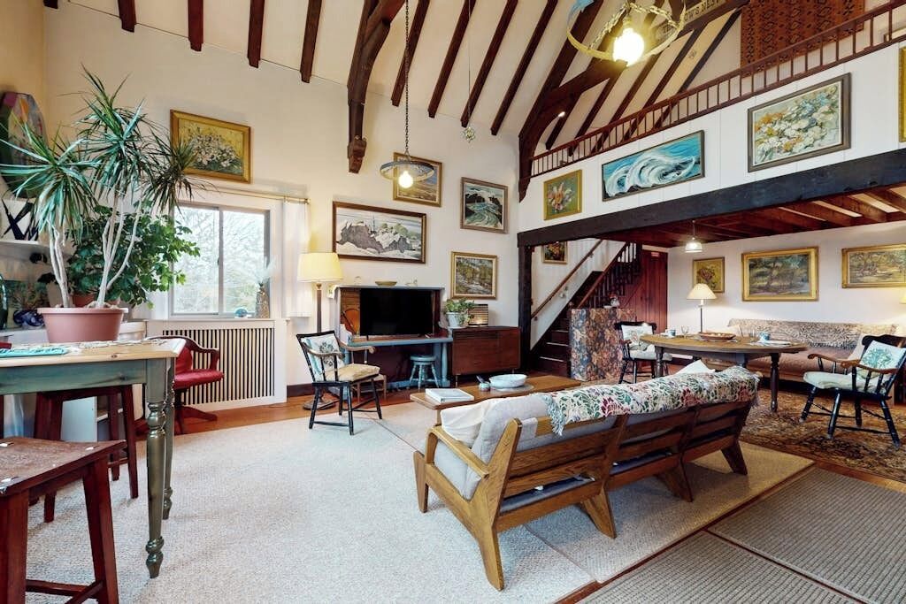 A spacious living area with a wooden bench, a dining table, and a staircase leading to an upper level.