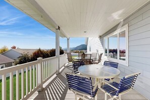 A covered patio with a round table and chairs, a white railing, and a view of the surrounding landscape. - Spacious home with pool table, WiFi, patio - close proximity to Flathead Lake (Kalispell)