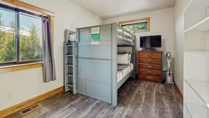 Ein Zimmer mit Etagenbetten, einem Fernseher, einem Schminktisch und einem Fenster mit Vorhängen.