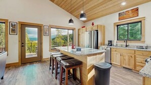 Eine moderne Küche mit Holzschränken, einem Edelstahlkühlschrank und einer großen Kochinsel mit Barhocker.