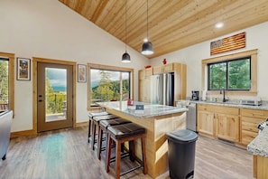 Eine moderne Küche mit Holzschränken, einem Edelstahlkühlschrank und einer großen Kochinsel mit Barhocker.