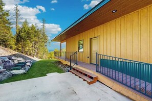 Ein Holzhaus mit einer Veranda, Treppen und einer Steinschmalseite.