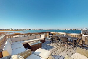 Una terraza con asientos al aire libre, vista al agua y una costa lejana.
