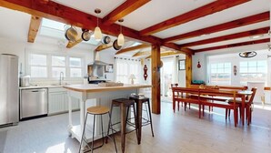 Una cocina amplia con vigas de madera, una isla central con taburetes y un comedor con bancos.