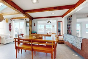 Amplia sala de estar con una mesa de comedor de madera, bancos, un sofá y una estantería.