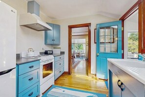 Eine Küche mit weißen Geräten, blauen Schränken und Holzboden.