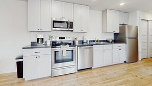 Una cocina moderna con armarios blancos, electrodomésticos de acero inoxidable y piso de madera.