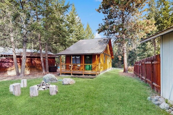 Eine Holzhütte mit Veranda, umgeben von Bäumen und einem Rasen.