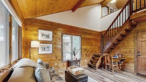 A cozy cabin interior with a wooden interior, a staircase, and a seating area with a sofa and ottoman. - Charming cabin in Big Fork, pet friendly, firepit, 5 min to Lake, fly-fishing (Bigfork)