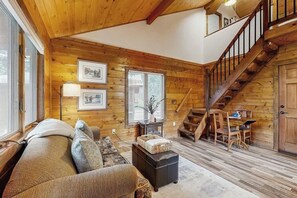 A wooden interior with a staircase, a sofa, a table, and framed pictures on the wall. - Enjoy two separate cabins, pet friendly, firepit, 5 min to Lake, fly-fishing (Bigfork)