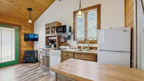 Una cocina con armarios de madera, estufa, microondas y refrigerador.