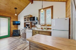 Eine Küche mit Holzschränken, einem Herd, einer Mikrowelle und einem Kühlschrank.