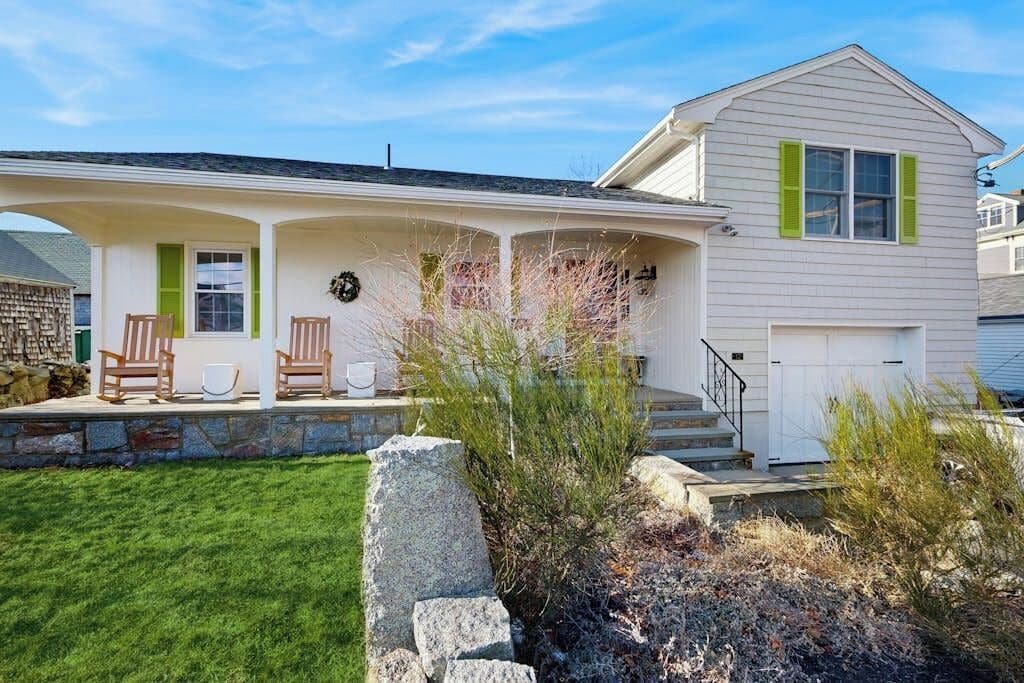 A two-story house with a covered porch, stone steps, and a front door.
