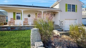 A two-story house with a covered porch, stone steps, and a front door. - Inviting coastal home w/ yard:  walk to beach, town & train (Rockport)