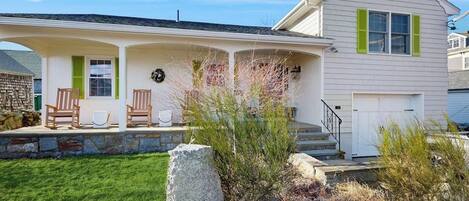 A two-story house with a covered porch, stone steps, and a front door.