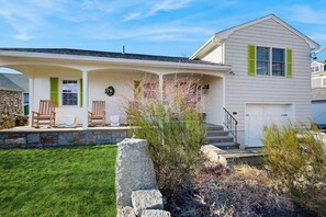 A two-story house with a covered porch, stone steps, and a front door.
