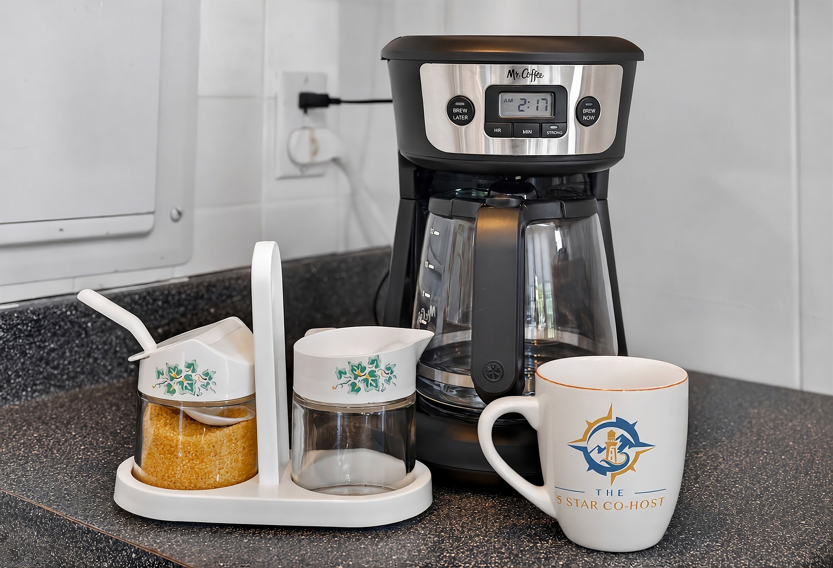 Een koffiezetapparaat, een koffiekan en een mok op een aanrecht.