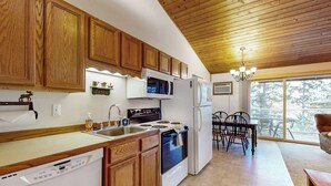 A kitchen with wooden cabinets, a dishwasher, a stove, a microwave, and a refrigerator. - Dog-friendly condo with lake view, hot tub & pool - near beach access (Whitefish)