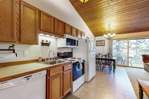 Una cocina con armarios de madera, lavavajillas, estufa, microondas y refrigerador.