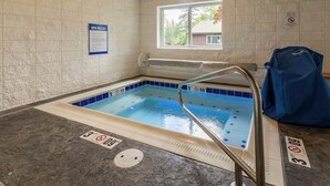 A spa pool with a blue tiled interior, a window with a view of trees, and a sign with spa rules. - Dog-friendly condo with lake view, hot tub & pool - near beach access (Whitefish)