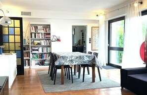 Un coin repas comprenant une table, des chaises, une bibliothèque et une vue par la fenêtre.