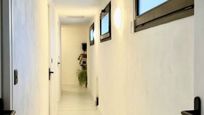 Un corridoio con pareti chiare, pavimento in legno e una porta a sinistra.