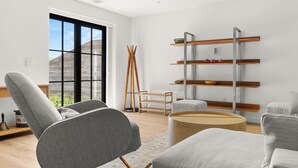 Una sala de estar moderna con un sofá gris, una mesa de centro redonda y una escalera de madera.