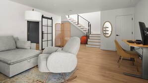 Una sala moderna con un sofá, un sillón mecedora, un escritorio con una computadora, una escalera y una puerta.