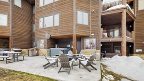 A multi-story building with a patio area featuring outdoor seating and a grill.