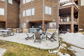 Ein mehrstöckiges Gebäude mit einer Terrasse, die Sitzgelegenheiten und einen Grill bietet.