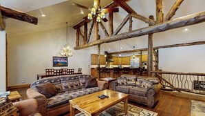 A rustic interior with exposed wooden beams, a wooden coffee table, and patterned sofas.