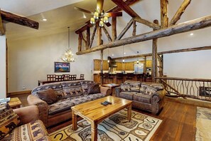 Ein rustikales Interieur mit freiliegenden Holzbalken, einem Holztisch und gemusterten Sofas.