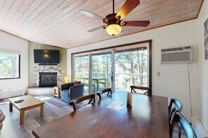 Un salón espacioso con chimenea, una mesa de comedor y un ventilador de techo.