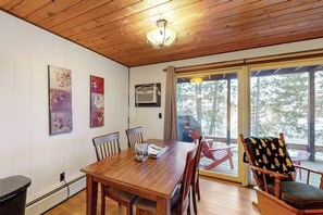 A wooden dining table with chairs, a ceiling fan, and artwork on the walls.
