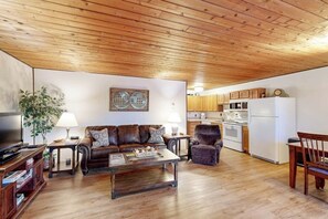 A living room with a wooden ceiling, a sofa, a coffee table, and a television.