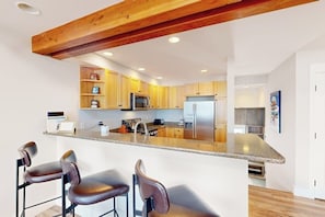 Eine moderne Küche mit Holzschränken, einem Edelstahlkühlschrank und einer Bar mit Sitzgelegenheiten.