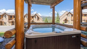 A hot tub in a wooden cabin with a view of other cabins and mountains. - Slopeside townhome with ski-in/ski-out and private hot tub (Big Sky)