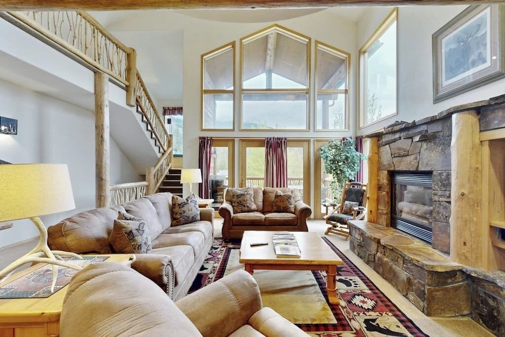 Ein geräumiges Wohnzimmer mit Kamin, einer Treppe und großen Fenstern.