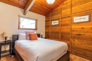 Ein Schlafzimmer mit Holzboden, einem Bett mit weißer Bettwäsche, zwei Nachttischen mit Lampen und gerahmten Bildern von Fischen an der Wand.