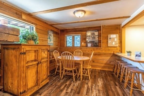 Ein Holzinnenraum mit Esstisch, Stühlen, einer Bar und einem Kühlschrank.