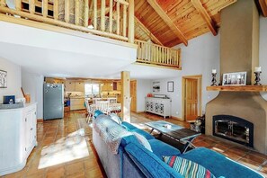 Ein geräumiger Wohnbereich mit hoher Decke, Kamin, Essbereich und Küche.