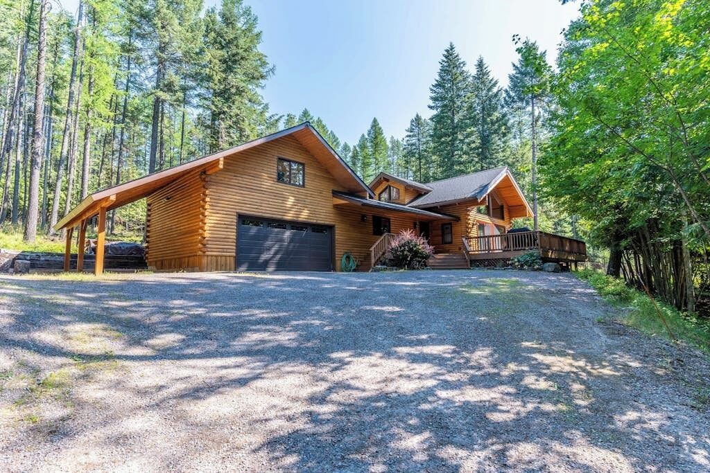 Eine Blockhütte mit Garage, umgeben von einem Wald.