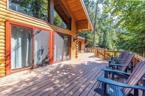 Eine Holzhütte mit einer Veranda, Sitzgelegenheiten im Freien und einem Wald im Hintergrund.