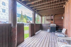 Eine überdachte Veranda mit Holzgeländern, einem Grill und Sitzgelegenheiten.