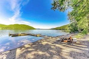 Blick auf einen See mit Steg, Picknicktisch und Bänken.