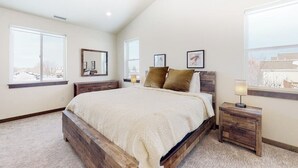 A bedroom with a large bed, two bedside tables, a window, and a ceiling fan. - Charming home with mountain view, fireplace, balcony, & washer/dryer (Belgrade)