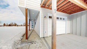 A building with a covered garage and a concrete pathway leading to a door. - Charming home with mountain view, fireplace, balcony, & washer/dryer (Belgrade)